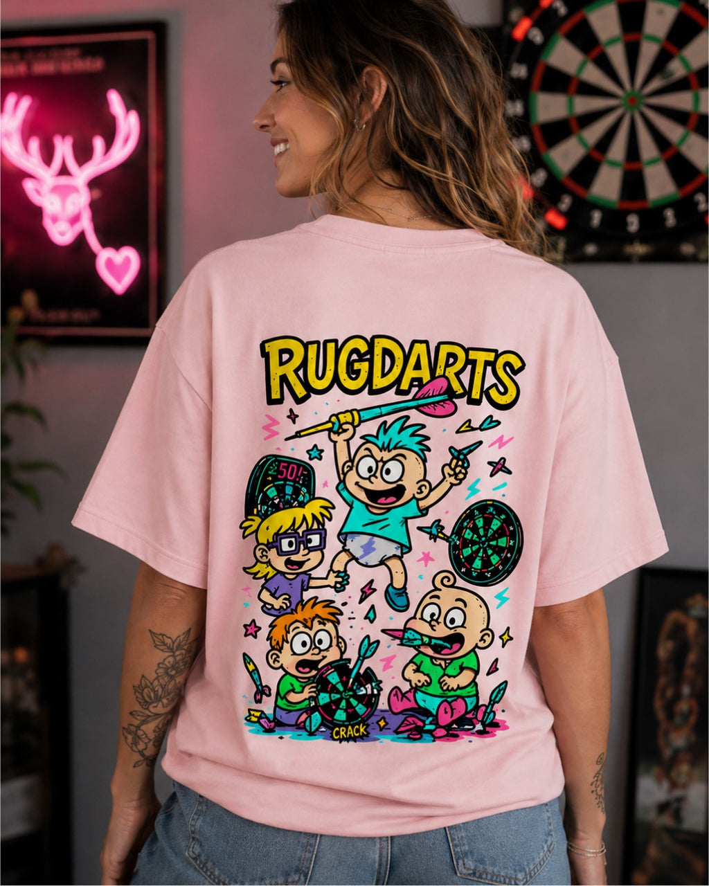 Chica de espaldas con la camiseta de dardos Rugdarts rosa y el diseño de bebés con dardos en la espalda