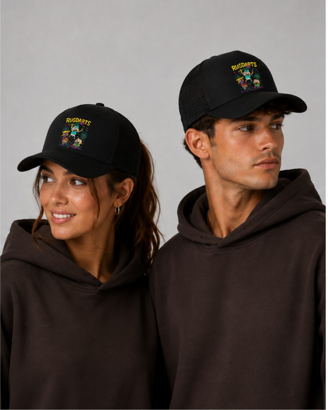 Chica y chico con la gorra de dardos Rugdarts negra y el diseño de bebés con dardos en el frontal